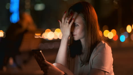 Una-Hermosa-Joven-En-Verano-En-Una-Gran-Ciudad-Nocturna-Mantiene-Un-Teléfono-Inteligente-En-Su-Interior-Y-Escribe-Un-Mensaje-Lee-Correos-Electrónicos-Y-Se-Comunica-En-Salas-De-Chat-Y-Redes-Sociales-Mantiene-Un-Blog-Mira-La-Pantalla-Del-Teléfono